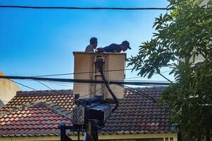 de openbaar werken afdeling is organiserende rommelig telecommunicatie en elektrisch kabels gebruik makend van een lucht optillen auto, Indonesië, 19 december 2023. foto