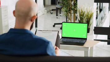 bedrijf arbeider met groene scherm Scherm herzien documenten, op zoek Bij Chroma sleutel blanco sjabloon in Open ruimte. zakenman gebruik makend van laptop en analytics voor geslaagd Onderzoek plan. foto