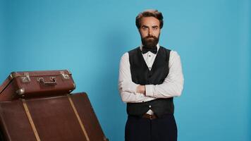 hotel conciërge met handschoenen poses in studio, klaar naar geven bijstand naar gasten met bagage. jong piccolo werknemer werken in toerisme reizen industrie, portier portier plicht. foto