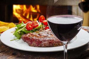 gebraden steak met salade, glas van rood wijn foto