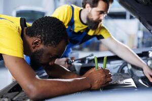 klusjesman en collega samenwerken Aan onderhoud gebroken voertuig, controle voor defect motor. gecertificeerd mechanica in auto reparatie winkel werken samen Aan vaststelling auto, bespreken het beste opties foto