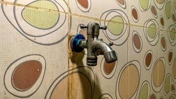 een water kraan gehecht naar een keramisch muur met een polka punt patroon foto