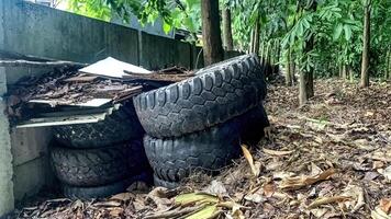 stapel van gebruikt auto banden Aan top van blad afval in de Woud foto