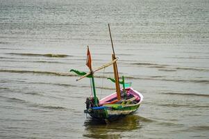 een houten visvangst boot met een klein Indonesisch vlag Aan het foto