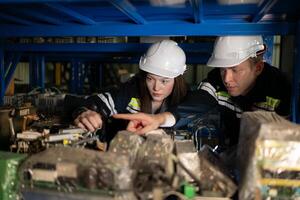 een jong vrouw ingenieur en een mannetje leidinggevende werk samen in robot arm Reserve onderdelen magazijn, robot arm industrie en bouwkunde concept. foto