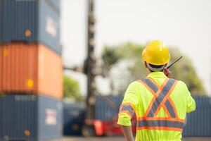 arbeiders in de importeren en exporteren industrie gebruik walkie talkies naar communiceren met chauffeurs van bereiken stapelaar containers in een leeg houder magazijn. foto