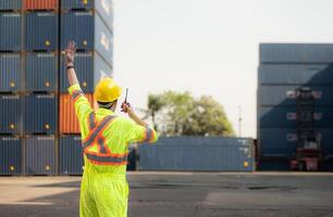 arbeiders in de importeren en exporteren industrie gebruik walkie talkies naar communiceren met chauffeurs van bereiken stapelaar containers in een leeg houder magazijn. foto