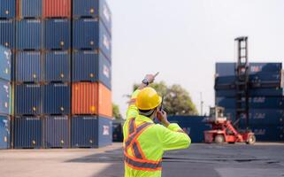 arbeiders in de importeren en exporteren industrie gebruik walkie talkies naar communiceren met chauffeurs van bereiken stapelaar containers in een leeg houder magazijn. foto