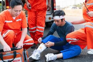 de paramedicus is assisteren een gewond Mens in een noodgeval situatie Aan de weg. foto