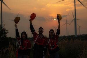 silhouet van groep ingenieurs en windmolens Aan de achtergrond van de instelling zon foto