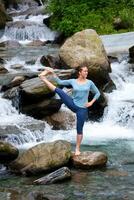 vrouw aan het doen Ashtanga Vinyasa yoga asana buitenshuis Bij waterval foto