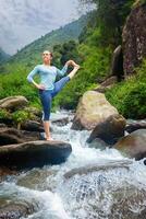 vrouw aan het doen Ashtanga Vinyasa yoga asana buitenshuis Bij waterval foto