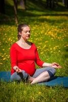 zwanger vrouw aan het doen asana Sukhasana buitenshuis foto