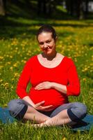 zwanger vrouw aan het doen asana Sukhasana buitenshuis foto