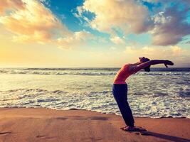 jong sportief fit vrouw aan het doen yoga zon begroeting surya namaskar foto