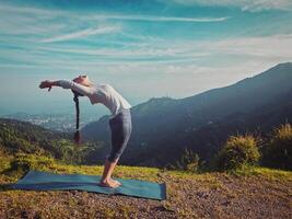 vrouw aan het doen yoga zon begroeting surya namaskar buitenshuis foto