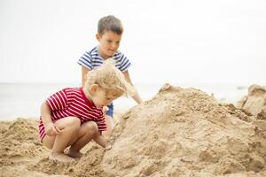 twee weinig jongens spelen Aan zanderig strand. schattig kinderen gebouw zandkastelen Aan strand foto