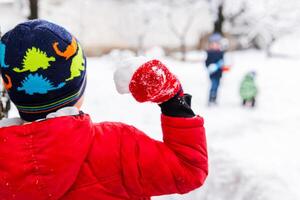 weinig kinderen spelen met sneeuwballen buitenshuis in de park foto