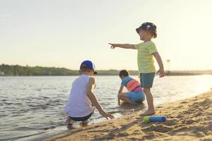 schattig kinderen hebben pret Aan de zanderig strand in zomer foto