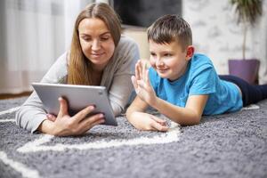 gelukkig moeder en zoon groet online op zoek Bij web camera gebruik makend van tablet pc foto