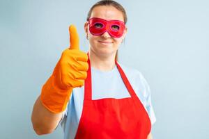 vrouw in rood masker, handschoenen en schort tonen duim omhoog. super huisvrouw foto