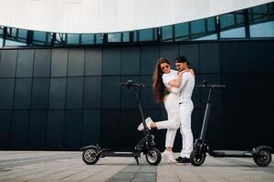 een meisje en een vent zijn wandelen Aan elektrisch scooters in de omgeving van de stad, een paar in liefde Aan scooters. foto