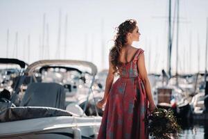 jong model- meisje in een mooi jurk met een boeket van bloemen Aan de strand in Frankrijk. meisje met bloemen in voorjaar provence Aan de Frans riviera foto