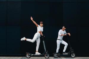 een meisje en een vent zijn wandelen Aan elektrisch scooters in de omgeving van de stad, een paar in liefde Aan scooters. foto