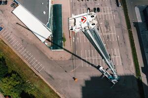 visie van de hoogte van de auto van een zwaar kraan met een wieg, welke is Open in de parkeren veel en klaar naar werk. de hoogste vrachtauto kraan is ingezet Aan de plaats. de hoogte van de boom is 80 meter foto