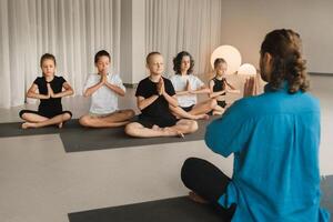 kinderen Doen yoga in de Sportschool onder de de begeleiding van een instructeur. kinderen gymnastiek foto