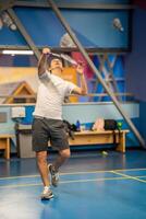Mens spelen badminton in sport slijtage Aan binnen- rechtbank foto