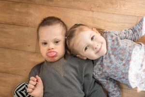 klein jongen met naar beneden syndroom Toneelstukken met zijn jonger zus in huis slaapkamer. hoog kwaliteit foto