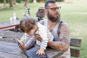 getatoeëerd vader hebben pret met zijn zoon en laptop foto