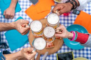 groep van mensen genieten van en roosteren een bier buitenshuis - detailopname Aan vier pint van bier foto