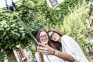 twee vrouw jong vrienden nemen een selfie omhelsd samen foto