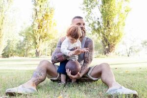 getatoeëerd vader hebben pret met zijn zoon in de park met rugby bal foto