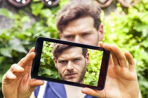 jong millennial Mens nemen een selfie met slim telefoon buitenshuis foto