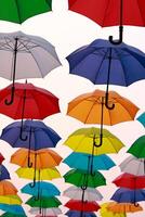 kleurrijk paraplu's en stedelijk straat decoratie. hangende kleurrijk paraplu's over- blauw lucht, toerist aantrekkingskracht, zonnig dag foto
