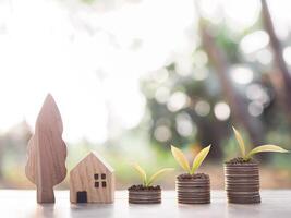 miniatuur huis en planten groeit omhoog Aan stack van munten. de concept van besparing geld voor huis, eigendom investering, huis hypotheek, echt landgoed. foto