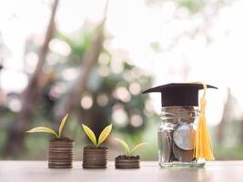 glas fles met diploma uitreiking hoed en planten groeit omhoog Aan stack van munten. de concept van besparing geld voor opleiding, leerling lening, studiebeurs, schoolgeld vergoedingen foto