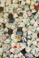 een groot aantal van petten van blikjes van aërosol verf voor graffitti. besmeurd met gekleurde verf mondstukken liggen in een reusachtig stapel foto
