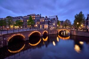 Amsterdam kanaal, brug en middeleeuws huizen in de avond foto