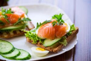 gebakken geroosterd brood met sla, ei, komkommers en rood vis in een bord. foto