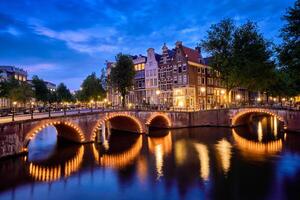 Amsterdam kanaal, brug en middeleeuws huizen in de avond foto