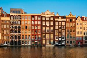huizen en toerist boten Aan Amsterdam kanaal pier damrak Aan zonsondergang foto