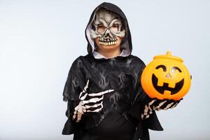 een jongen vervelend halloween kostuum met pompoen mand Aan blauw achtergrond foto
