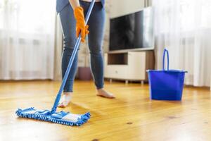 persoon schoonmaak verdieping met dweilen en emmer foto