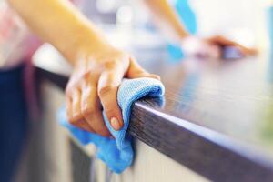 vrouw hand- schoonmaak de teller in de keuken met een blauw microfiber kleding foto