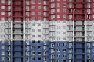Nederland vlag afgebeeld in verf kleuren Aan meerdere verdiepingen woonachtig gebouw onder bouw. getextureerde banier Aan steen muur achtergrond foto