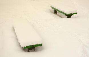 de bank, gedekt door een dik laag van een muur, is gelegen Aan een met sneeuw bedekt platform foto